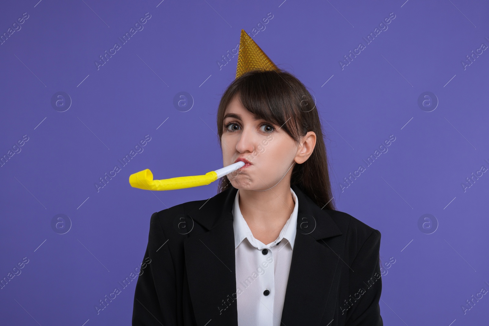 Photo of Woman in party hat with blower on purple background