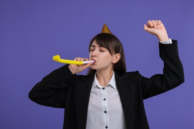 Photo of Woman in party hat with blower on purple background