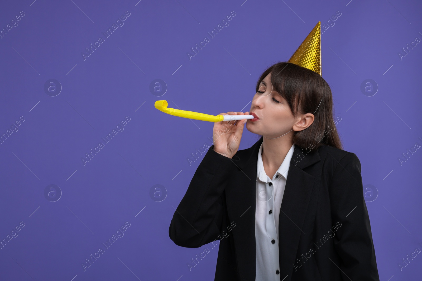 Photo of Woman in party hat with blower on purple background, space for text