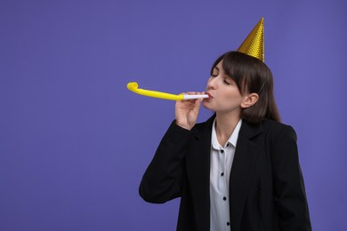 Woman in party hat with blower on purple background, space for text