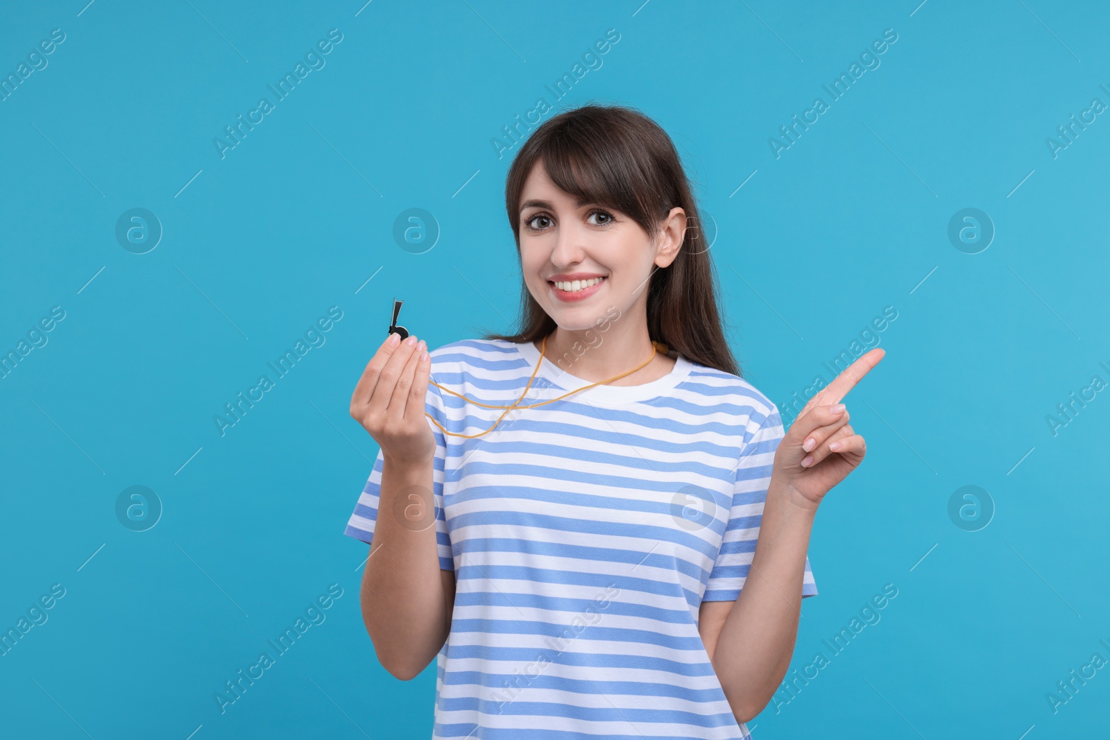 Photo of Happy woman with whistle on light blue background