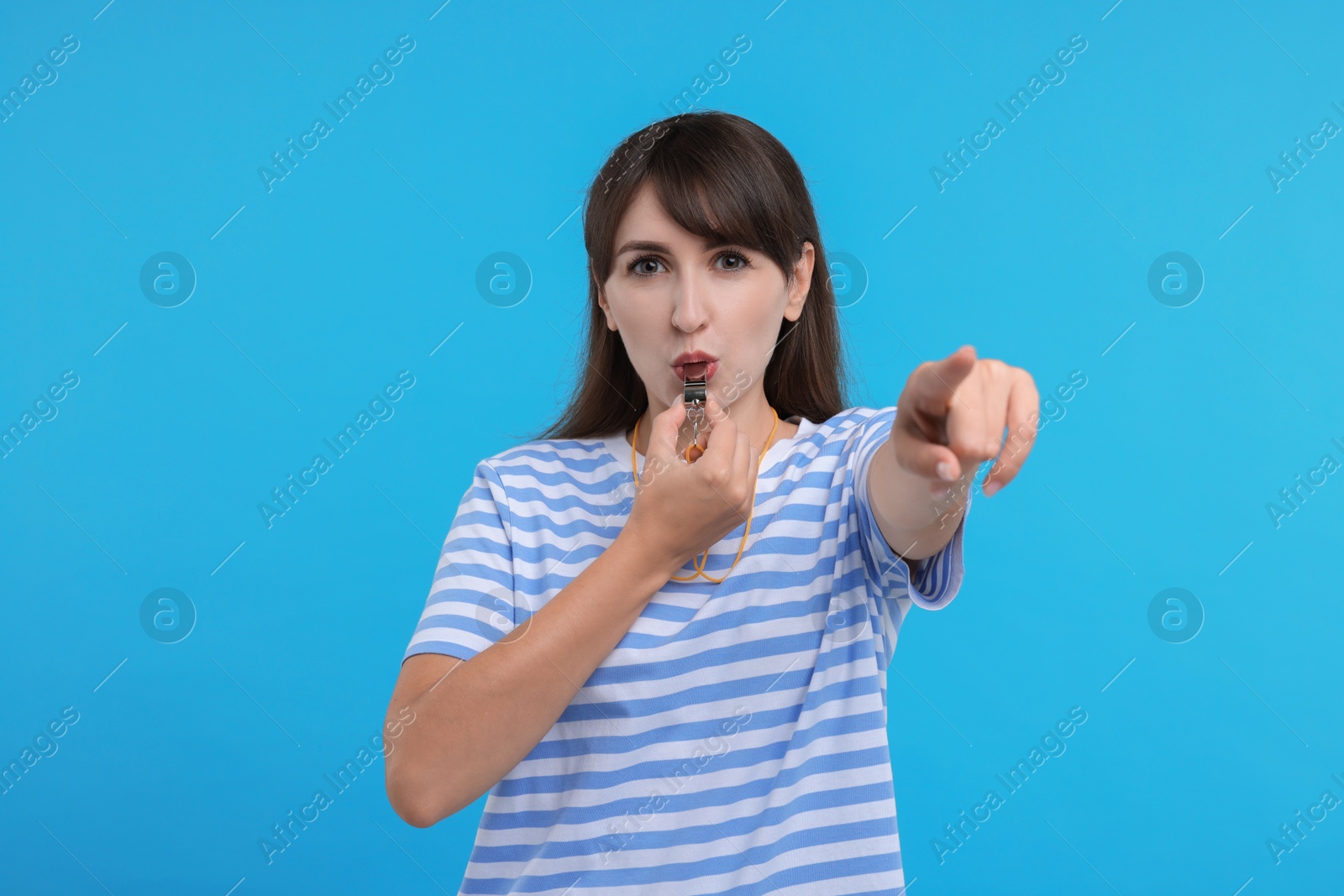 Photo of Woman blowing whistle on light blue background