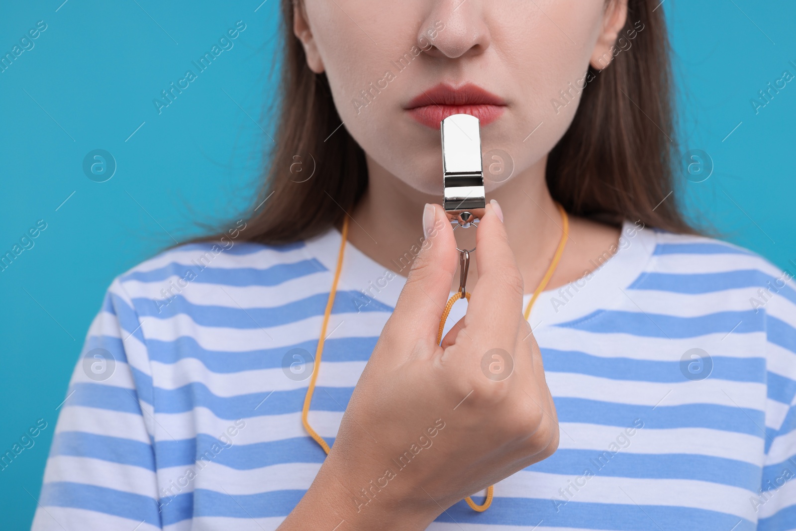 Photo of Woman with whistle on light blue background, closeup