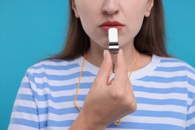 Photo of Woman with whistle on light blue background, closeup