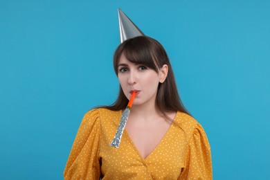 Photo of Woman in party hat with blower on light blue background