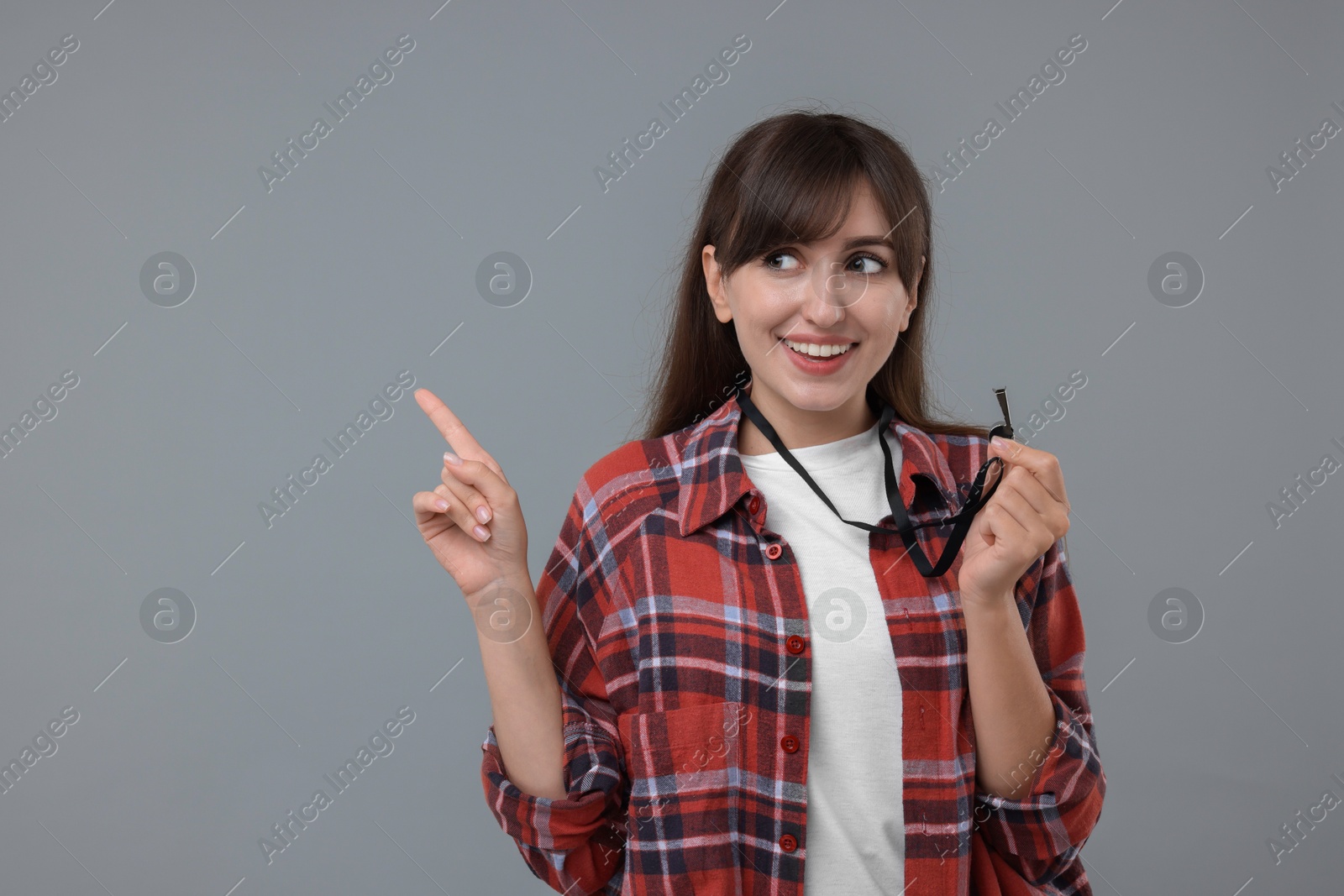 Photo of Happy woman with whistle on grey background, space for text