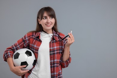 Happy woman with whistle and soccer bal on grey background, space for text