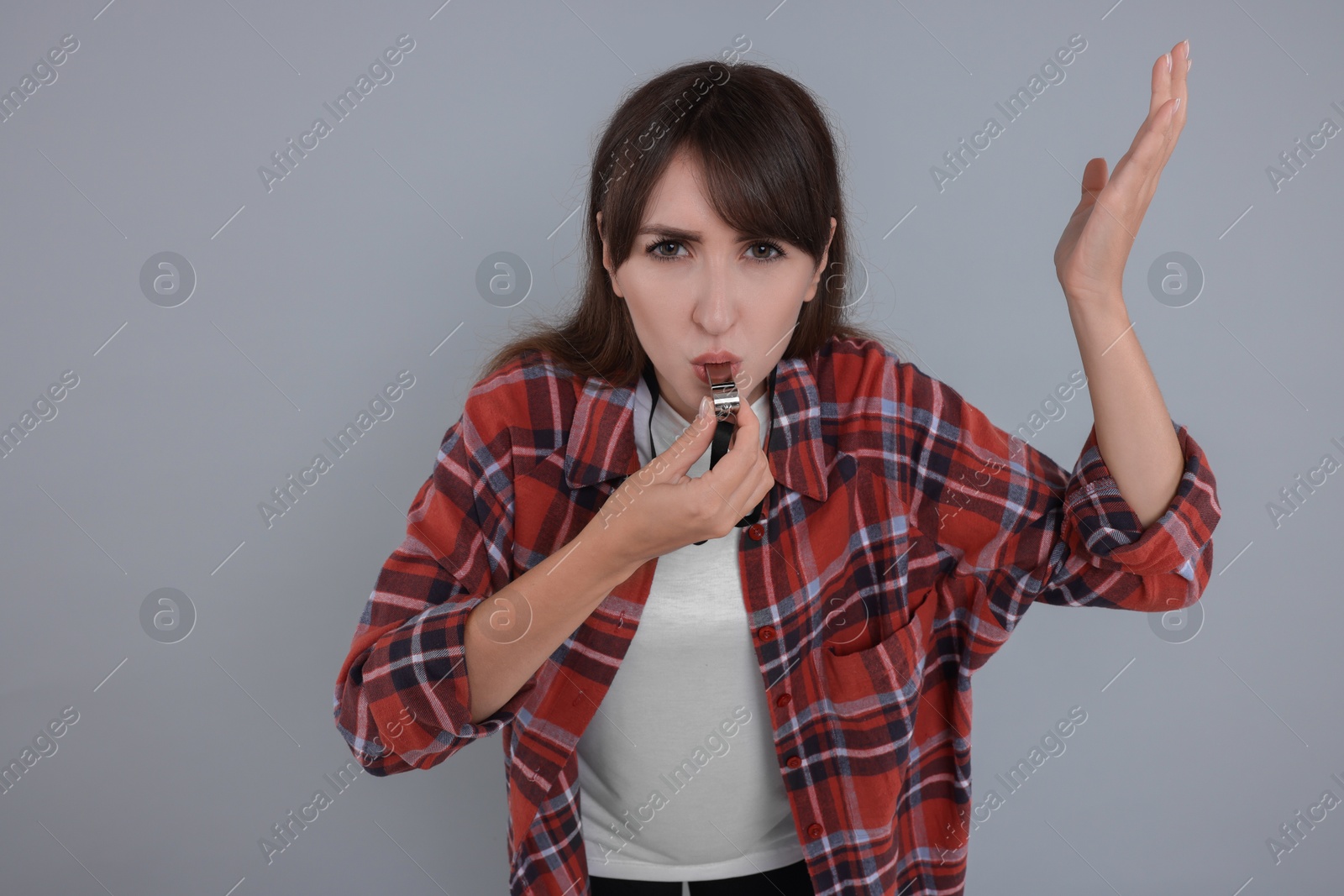 Photo of Young woman blowing whistle on grey background