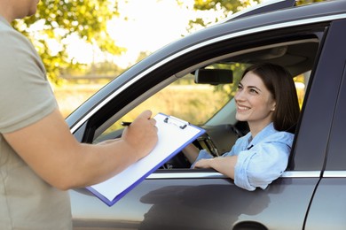 Examiner near car with student during test at driving school