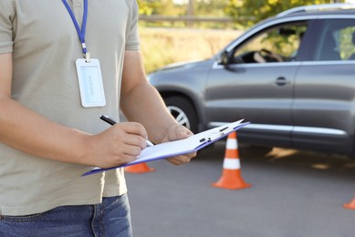 Examiner with clipboard during exam at driving school test track, closeup