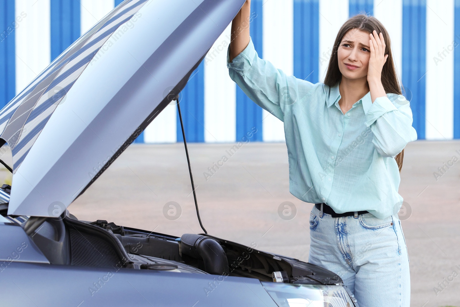 Photo of Stressed woman standing near broken car outdoors