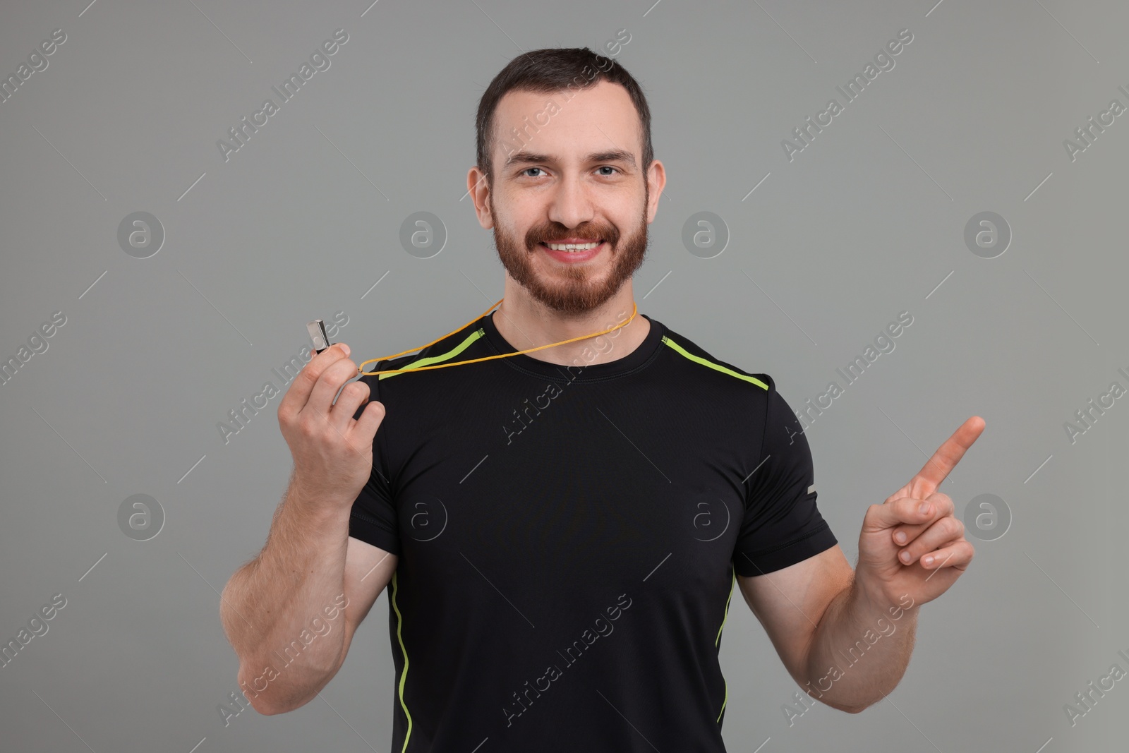 Photo of Happy young man with whistle on grey background