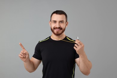 Happy young man with whistle on grey background