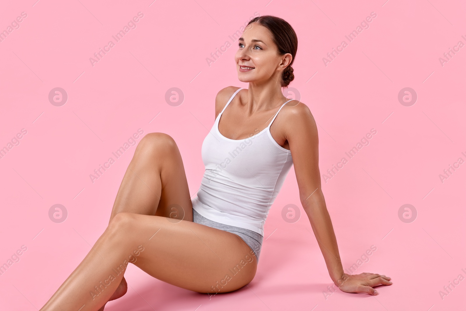 Photo of Smiling woman with perfect skin posing on pink background. Body care