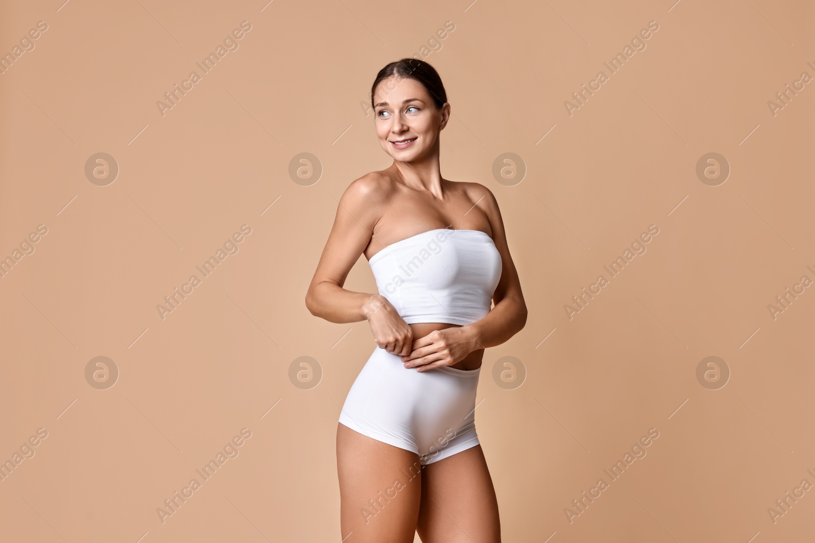 Photo of Smiling woman with perfect skin posing on beige background. Body care