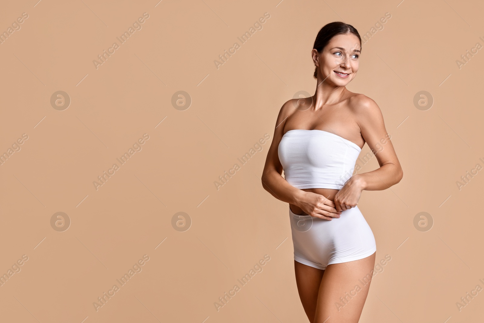 Photo of Smiling woman with perfect skin posing on beige background, space for text. Body care