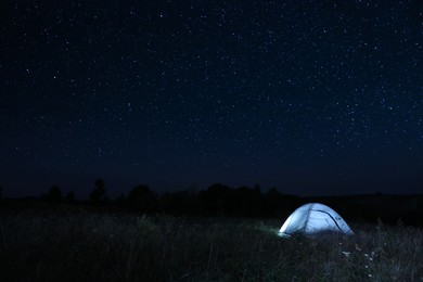 Photo of Modern camping tent in wilderness at night