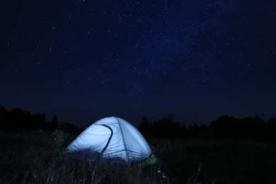 Photo of Modern camping tent in wilderness at night