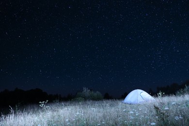 Photo of Modern camping tent in wilderness at night