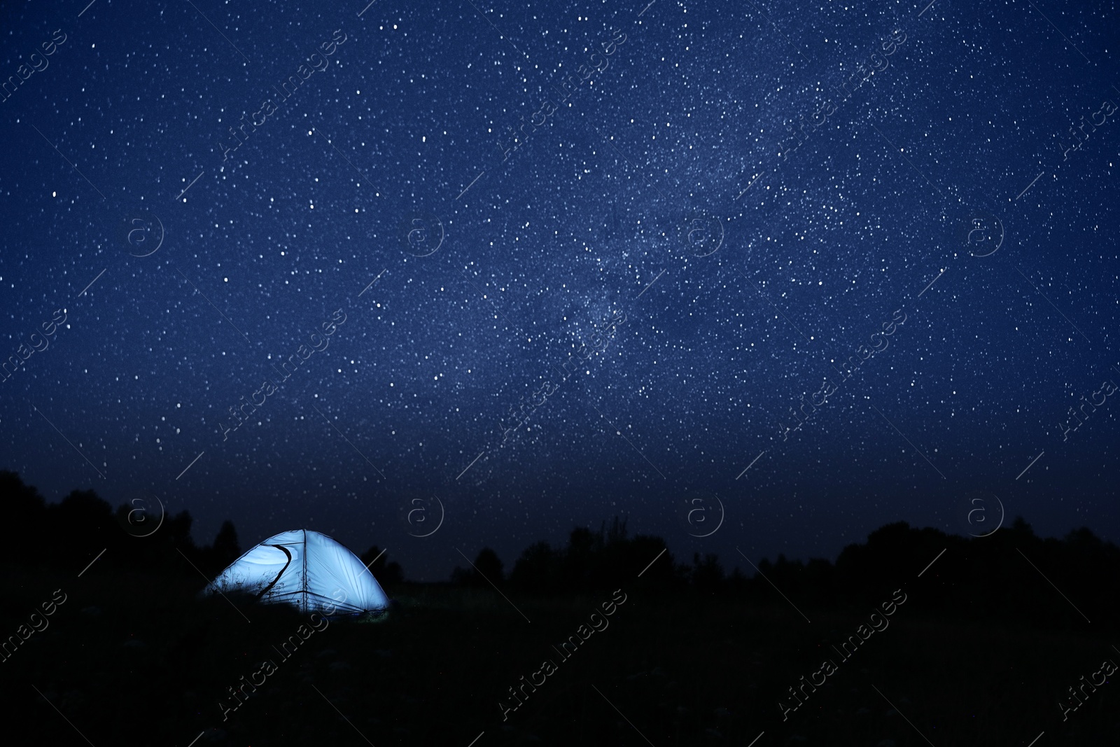 Photo of Modern camping tent in wilderness at night