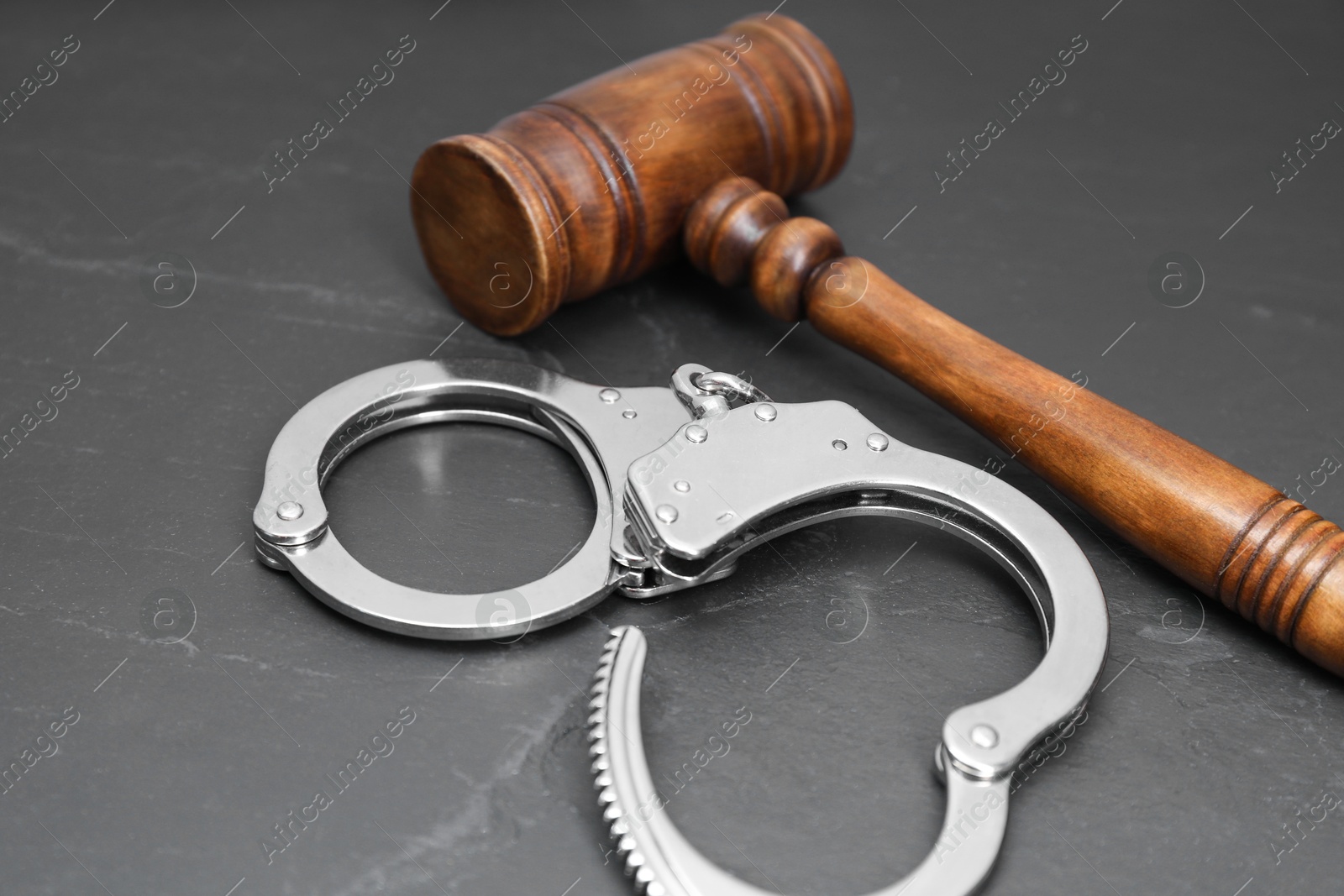 Photo of Judge's gavel and handcuffs on gray textured table, closeup