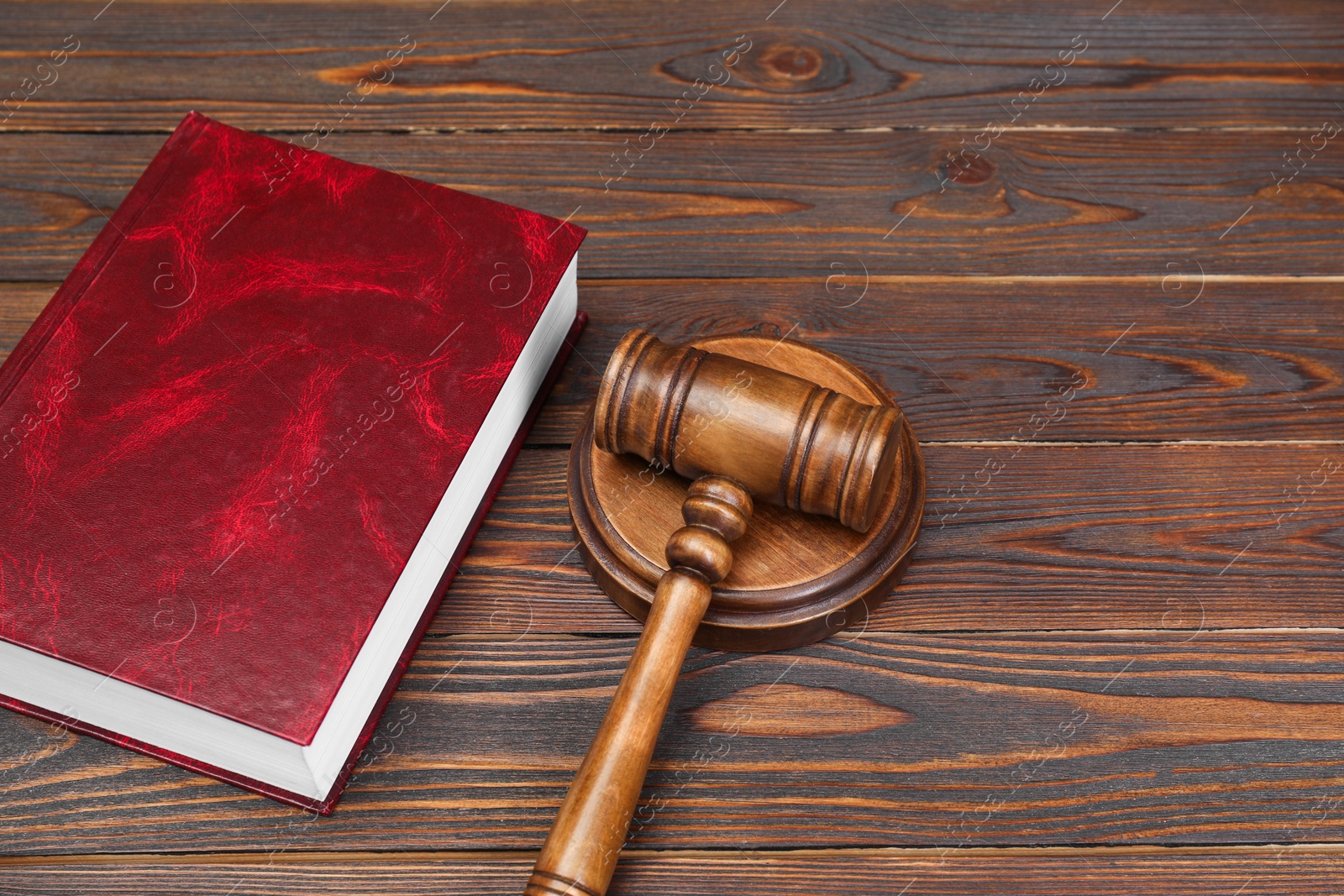 Photo of Book and judge's gavel on wooden table. Space for text