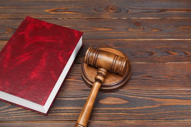 Book and judge's gavel on wooden table. Space for text