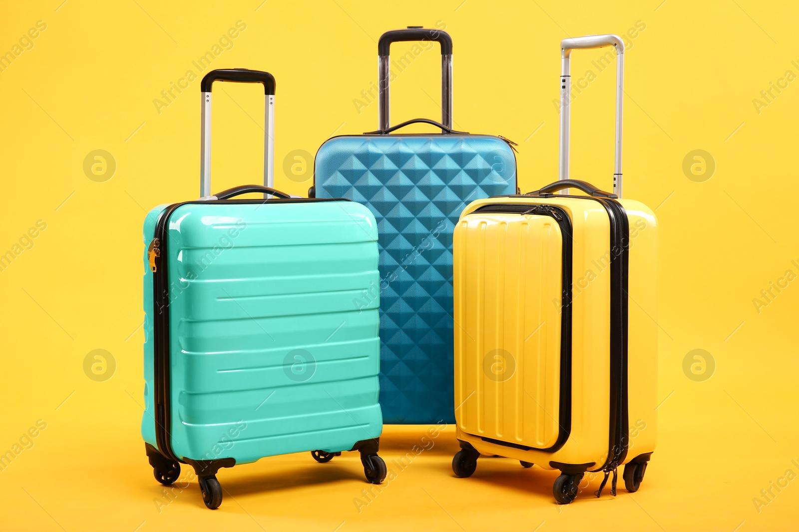 Photo of Three different bright suitcases on yellow background