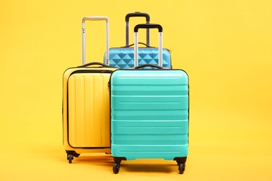 Three different bright suitcases on yellow background