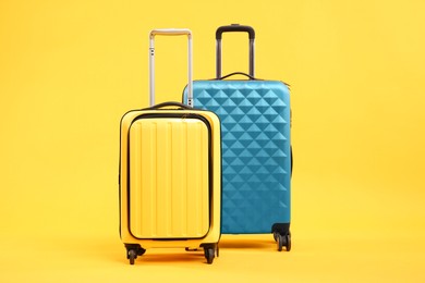 Photo of Two different bright suitcases on yellow background