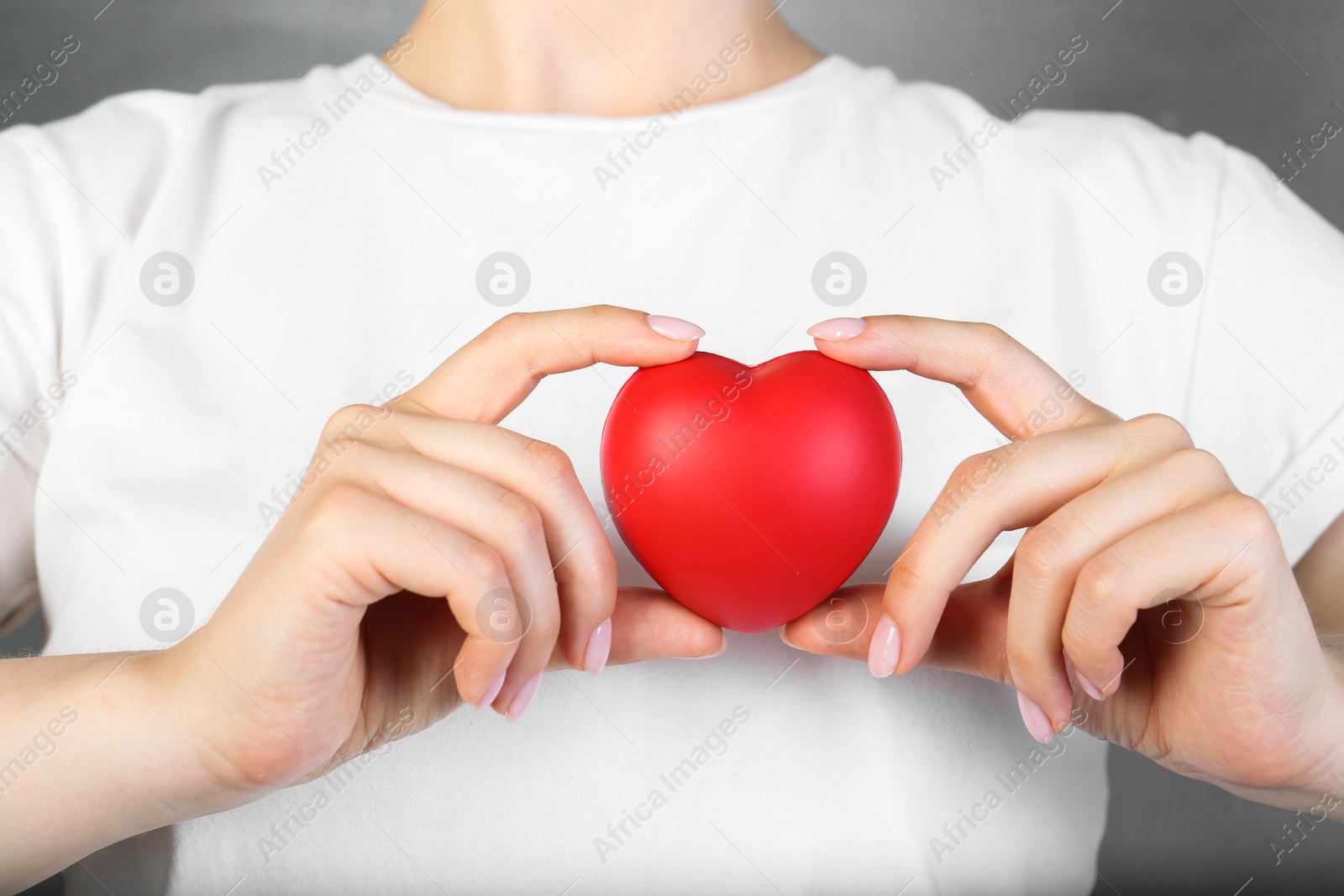 Photo of Woman holding red heart on grey background, closeup