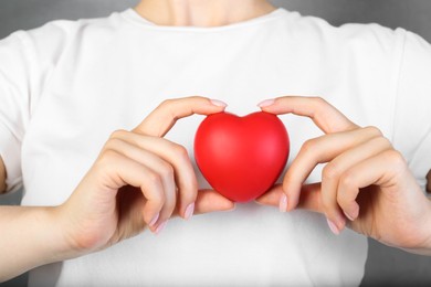 Photo of Woman holding red heart on grey background, closeup