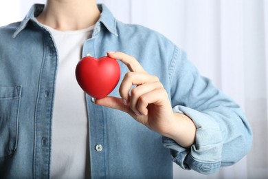 Photo of Woman holding red heart on light background, closeup