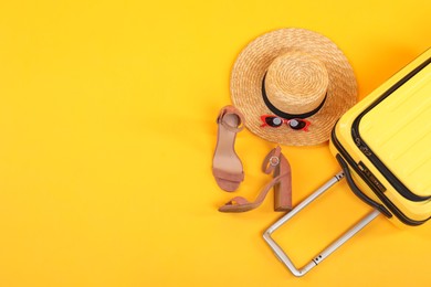 Photo of Suitcase with wicker hat, sunglasses and shoes on yellow background, flat lay. Space for text