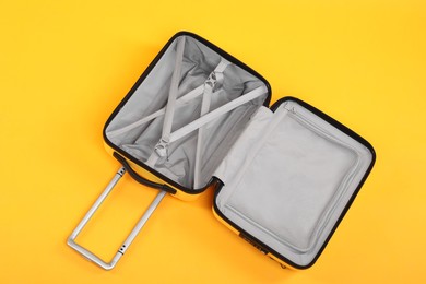 Photo of Open empty suitcase on yellow background, top view