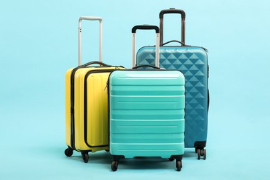 Different bright suitcases on light blue background