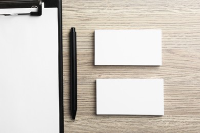 Photo of Blank business cards, clipboard with sheet and pen on wooden table, flat lay. Mockup for design