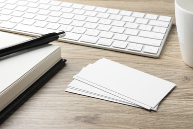 Blank business cards, notebook, pen and keyboard on wooden table. Mockup for design