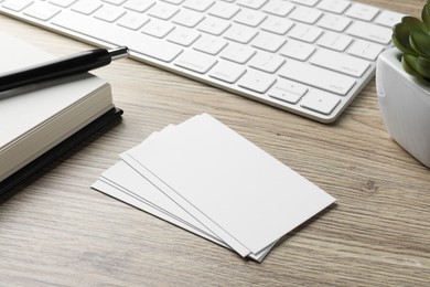 Photo of Blank business cards, notebook, pen and keyboard on wooden table. Mockup for design