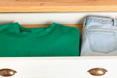 Chest of drawers with different folded clothes, closeup