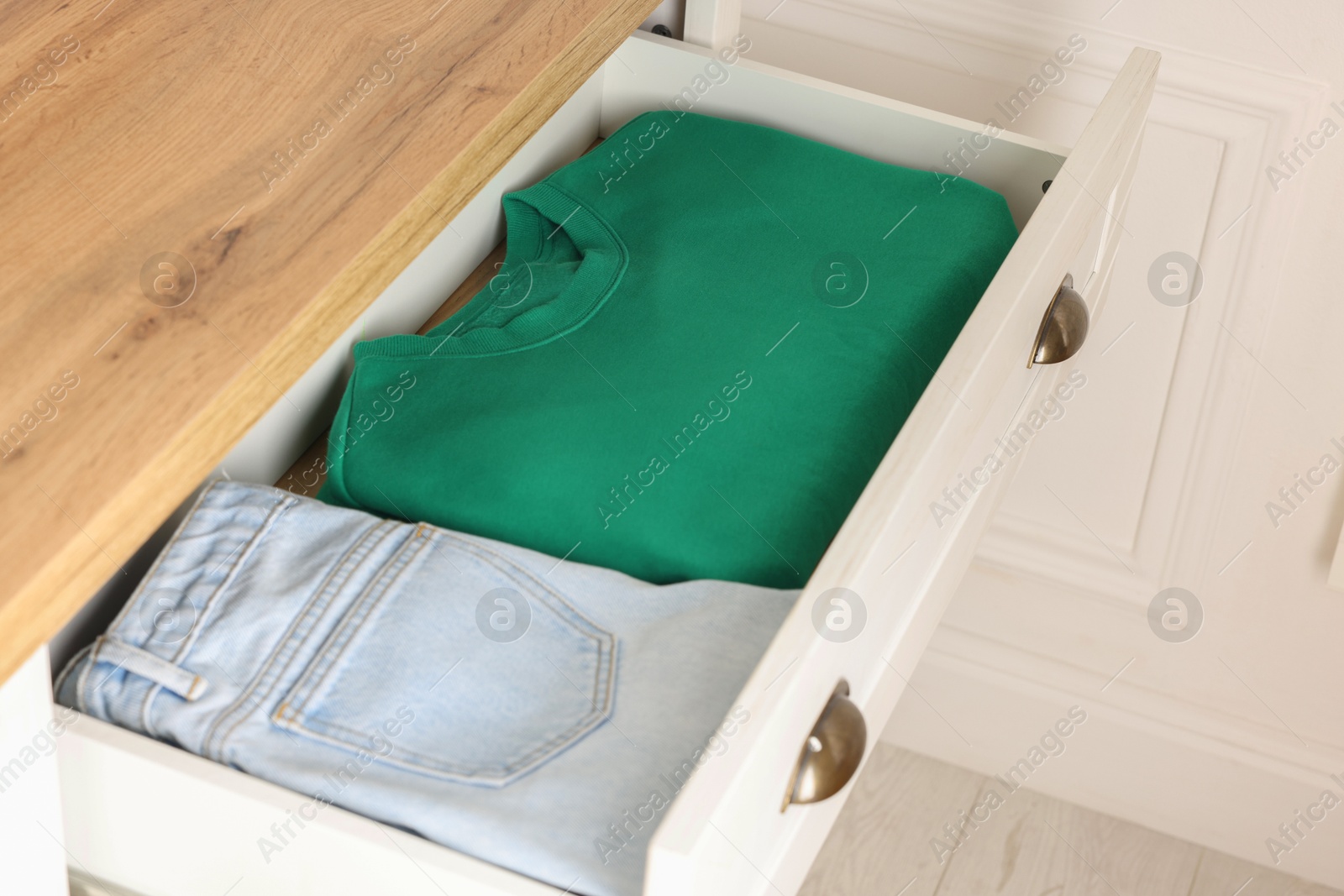 Photo of Chest of drawers with different folded clothes, closeup