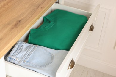 Chest of drawers with different folded clothes, closeup