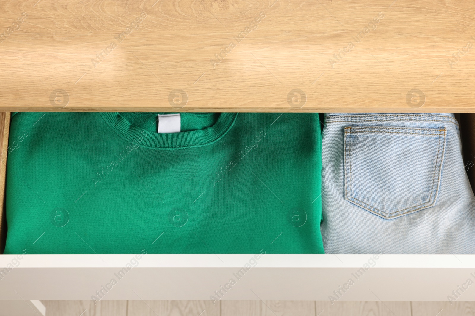 Photo of Chest of drawers with different folded clothes, above view