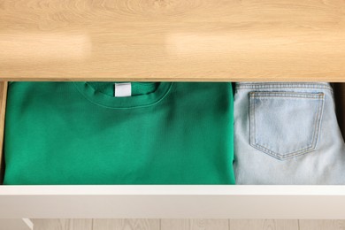 Chest of drawers with different folded clothes, above view