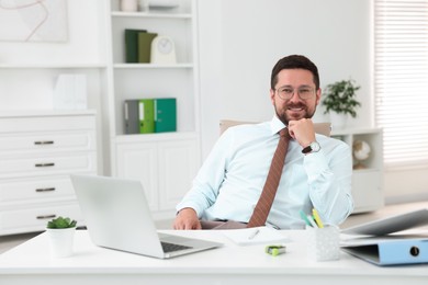 Photo of Portrait of smiling businessman at table in office