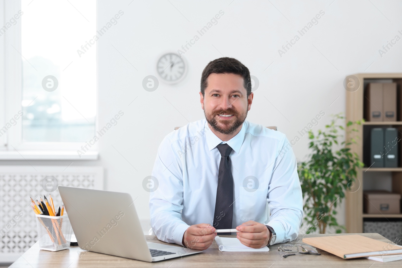 Photo of Portrait of smiling businessman at table in office