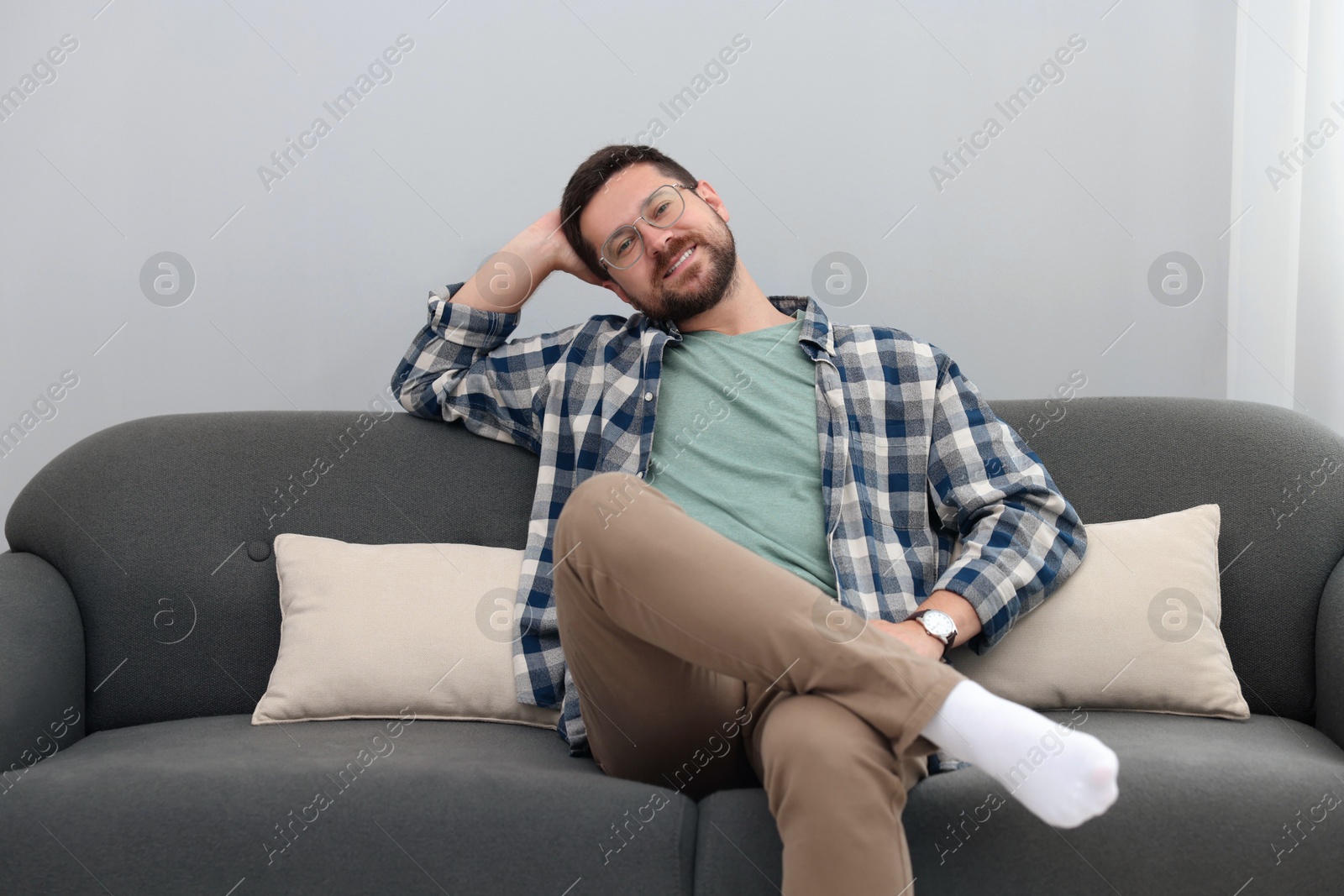 Photo of Smiling man relaxing on sofa at home