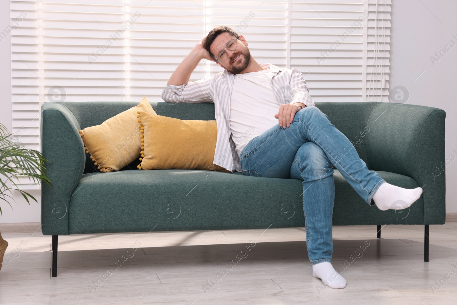 Photo of Smiling man relaxing on sofa at home