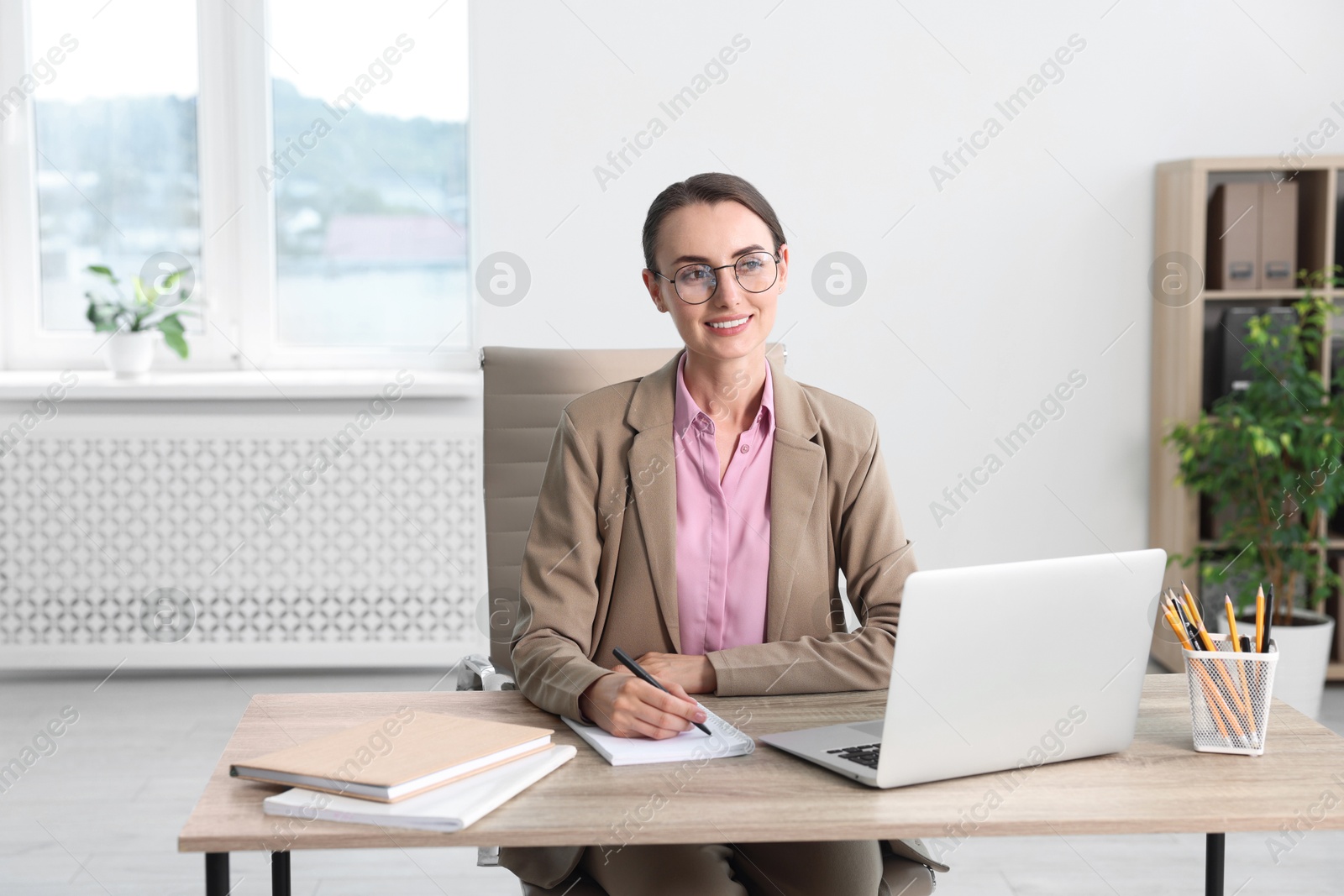 Photo of Smiling businesswoman working at table in office