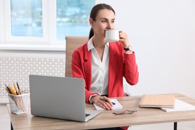 Businesswoman drinking coffee at table in office. Break time